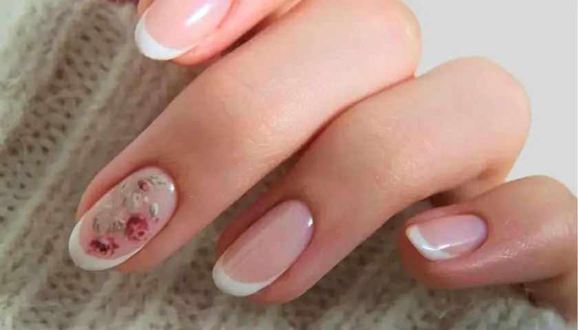Delikatne paznokcie ślubne boho z subtelnym zdobieniem w postaci różowych kwiatów na jednym z paznokci. Klasyczny french manicure w nowoczesnym wydaniu.